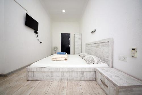 a white bedroom with a bed and a tv at Hostel Mandaria in Kutaisi