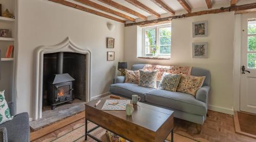 a living room with a couch and a fireplace at Alba Cottage, Wilcot, Pewsey 