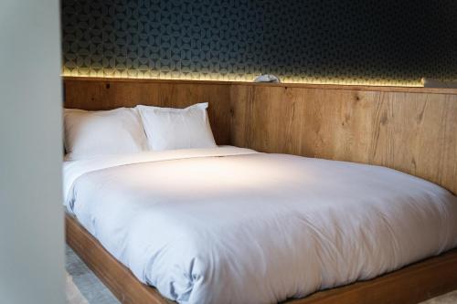 a large bed with white sheets and pillows at SAUNALAND ASAKUSA in Tokyo