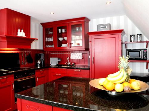 - une cuisine rouge avec un bol de fruits sur un comptoir dans l'établissement Ferienwohnungen Schimsheimer Rhode, à Olpe