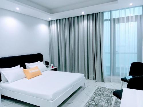 a bedroom with a white bed and a large window at Al Safwa One in Al Ḩadd