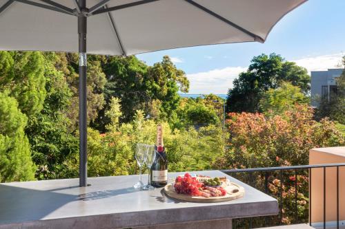 a bottle of wine and a plate of food on a table with an umbrella at L'Auberge Noosa in Noosa Heads