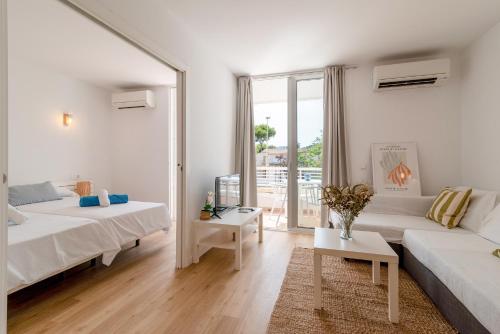 a white living room with two beds and a table at Bellamar Apartments in Port d'Alcudia
