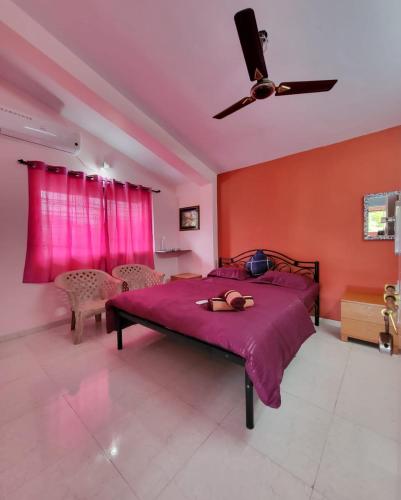 a bedroom with a bed with pink walls and a ceiling fan at THE PERFECT STAYS- Lal Mahal Villa with Disco pool in Lonavala