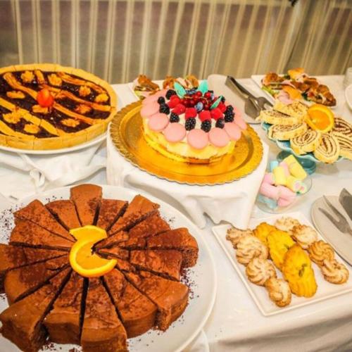 uma mesa com bolos e outros alimentos em Hotel Gambrinus - Valentini Family Village em Bellaria-Igea Marina