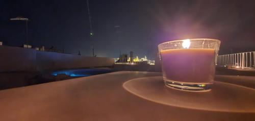 a glass of liquid sitting on a table with a candle at Via Roma 32 in Ostuni