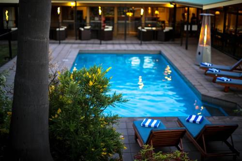 a swimming pool with chairs and a table in a hotel at Quality Inn Dubbo International in Dubbo
