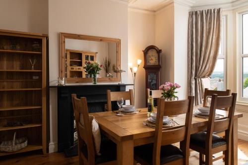 une salle à manger avec une table en bois et une horloge dans l'établissement Beautiful Townhouse on The Great Orme, Llandudno PET FRIENDLY, à Llandudno