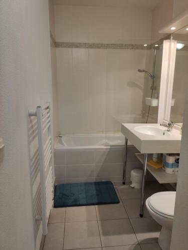 uma casa de banho com uma banheira, um WC e um lavatório. em Superbe appartement avec piscine sauna et petite vue mer em Plougonvelin