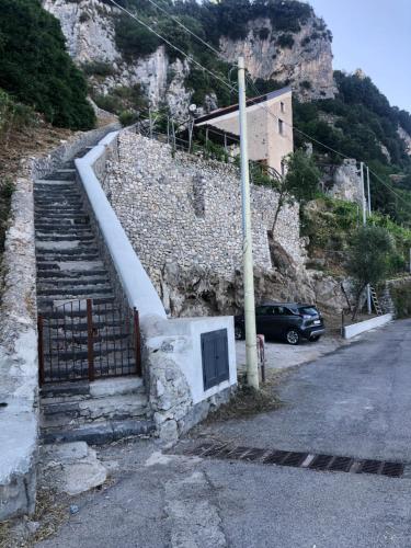 a building on a hill with a gate and a car at Il Nido Del Falco - Art house with terrace and sea view in Furore
