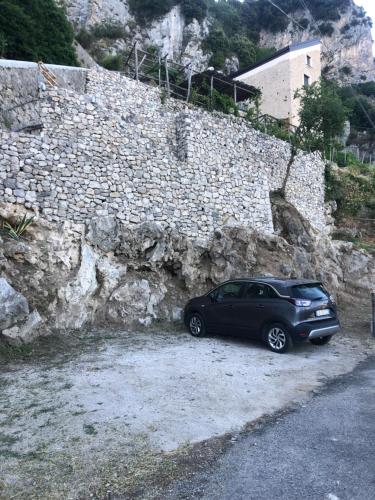 a black car parked next to a stone wall at Il Nido Del Falco - Art house with terrace and sea view in Furore
