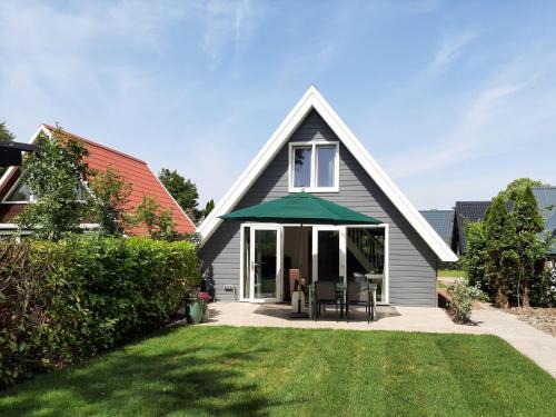 a house with a green umbrella and a lawn at Stylish holiday home by the sea in Tuitjenhorn