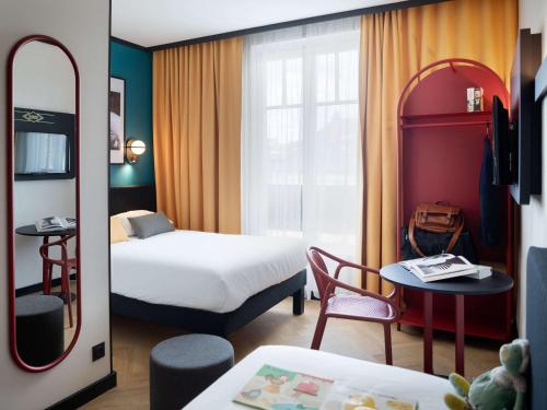 um quarto de hotel com um quarto com uma cama e uma mesa em ibis Styles Dijon Central em Dijon