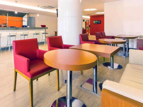 a waiting room with tables and red chairs at Ibis Mossoro in Mossoró