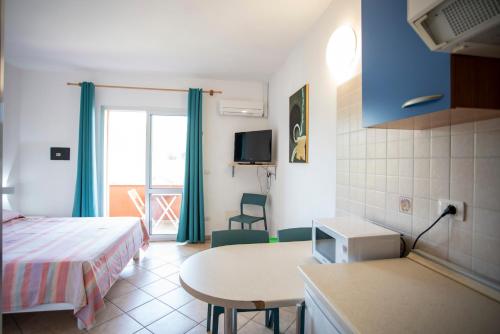 a room with a bed and a table and a kitchen at Residence Reale in Porto Azzurro
