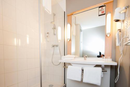 La salle de bains est pourvue d'un lavabo et d'une douche. dans l'établissement ibis Calais Car Ferry, à Calais