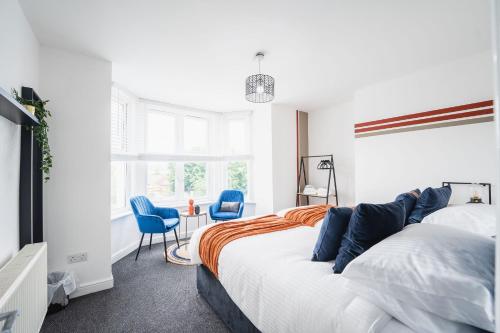 a bedroom with a bed and two blue chairs at Kandaka-Modern Apartment in Belle Isle