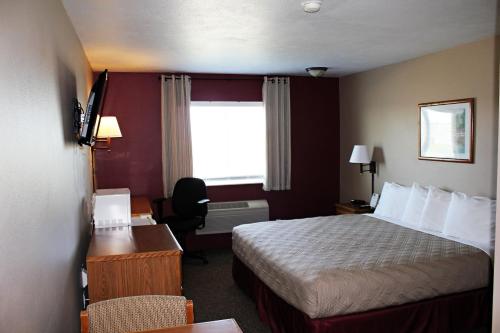 a hotel room with a bed and a desk at Capri Inn & Suites - Beatrice in Beatrice