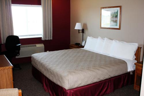a hotel room with a bed and a desk and a window at Capri Inn & Suites - Beatrice in Beatrice