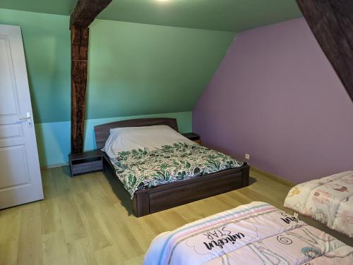 two beds in a room with green walls and wooden floors at Chez Patrick et Émilie in Bragelogne