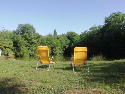 dwa żółte krzesła siedzące w trawie na polu w obiekcie Vlajina brvnara w mieście Arandelovac