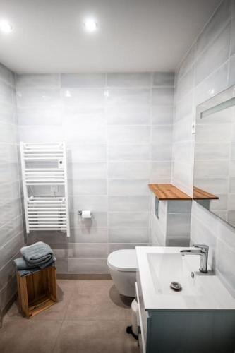 a white bathroom with a toilet and a sink at APPART-DUPLEX VUE MER PANORAMIQUE BALCON & PISCINE proche commerce in Penmarcʼh