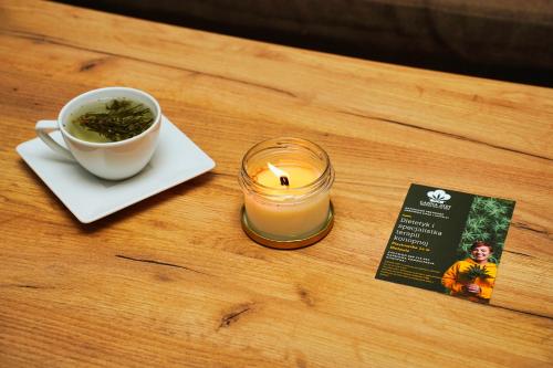 a candle and a cup of tea and a book on a table at Sudety Canna House in Bielawa