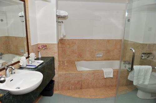 a bathroom with a tub and a sink and a toilet at Grand Riverview Hotel in Kota Bharu