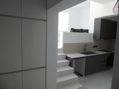a kitchen with white cabinets and a sink and stairs at Skala Sunset Hotel and spa in Ios Chora