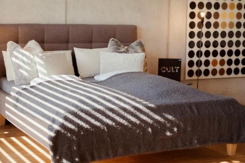 uma cama com um edredão cinzento e almofadas brancas em Loft-Apartment - Bestlage am Kurpark mit Terrasse - kostenloses Parken - Küche - Netflix - Waschmaschine em Wiesbaden