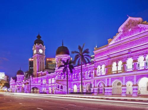 un edificio illuminato in viola con una torre dell'orologio di Swiss Hotel Kuala Lumpur a Kuala Lumpur