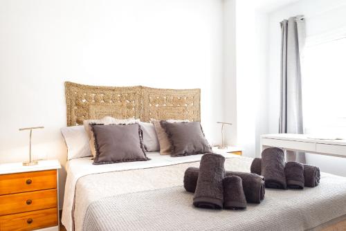a white bedroom with a large bed with brown pillows at Casa Nadia in Corralejo