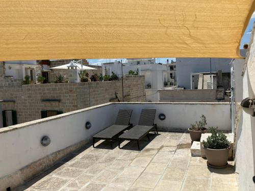 a patio with two benches on a roof at Tresor 65 in Polignano a Mare