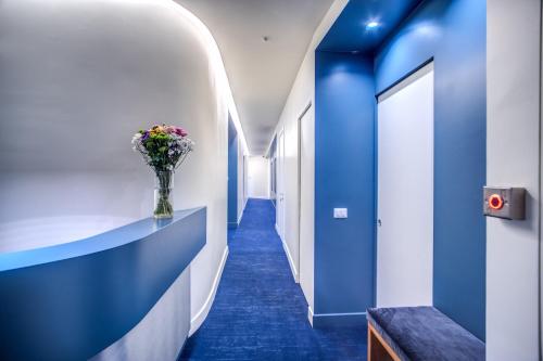 a hallway with blue walls and a vase of flowers at Sheva Boutique Hotel in Milan