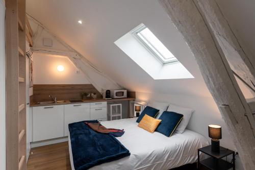 una camera da letto con un letto bianco con cuscini blu di Les Clés de La porte Saint-Nicolas - Parking - Centre a Beaune