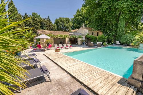 une piscine avec des chaises et une maison dans l'établissement Mas des Fontètes, à Fontvieille