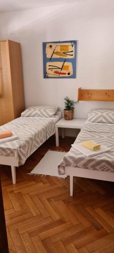 a room with two beds and a painting on the wall at Apartments Dora in Pag