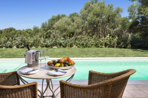 a table with a bowl of fruit next to a pool at Stazzo Lu Ciaccaru in Arzachena