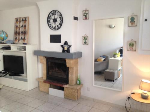 a living room with a fireplace and a clock on the wall at Maison de centre ville 6 personnes in Précigné