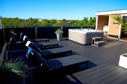 a deck with a hot tub and benches on a balcony at Willa Agnieszka in Jastrzębia Góra