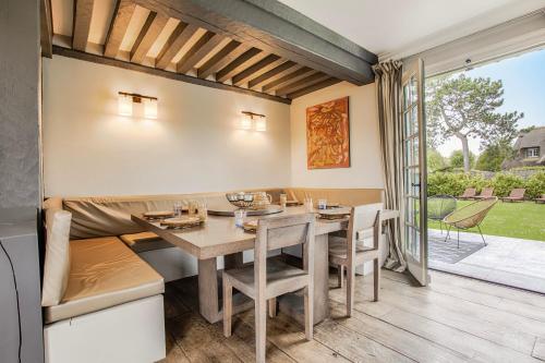 a dining room with a table and chairs and a patio at Luxueuse Chaumière 4 Chambres avec jardin in Deauville
