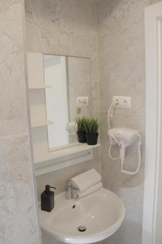 a white bathroom with a sink and a mirror at Hauptbahnhof S2 in Vienna