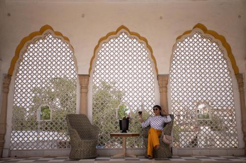 a woman standing in a room with three arched windows at Diggi Palace - A City Center Hidden Heritage Gem in Jaipur