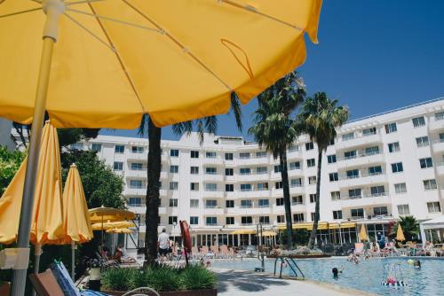 a hotel with a swimming pool with umbrellas and a hotel at Hotel Ivory Playa Sports & Spa in Port d'Alcudia