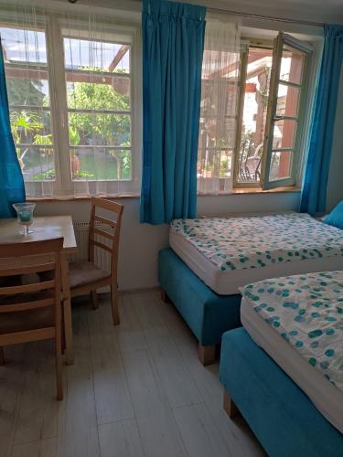 a room with two beds and a table and chairs at Patak28 Apartmanok in Sopron