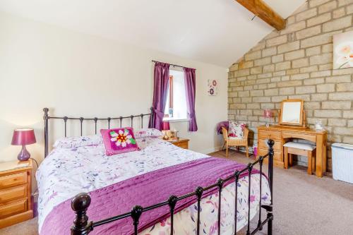a bedroom with a large bed with a purple comforter at Jenny's Cottage in Oldham