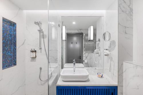 a white bathroom with a sink and a shower at Danubius Hotel Astoria City Center in Budapest