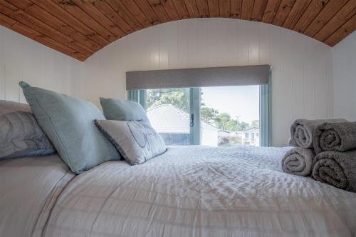 a bedroom with a large bed with a large window at Rosemary - 1 Bedroom Shepherds Hut - Amroth in Amroth