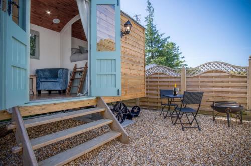a backyard with a tiny house with a table and chairs at Rosemary - 1 Bedroom Shepherds Hut - Amroth in Amroth