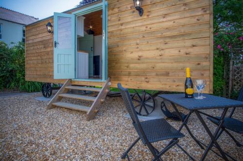 a tiny house with a table and a bottle of wine at Rosemary - 1 Bedroom Shepherds Hut - Amroth in Amroth